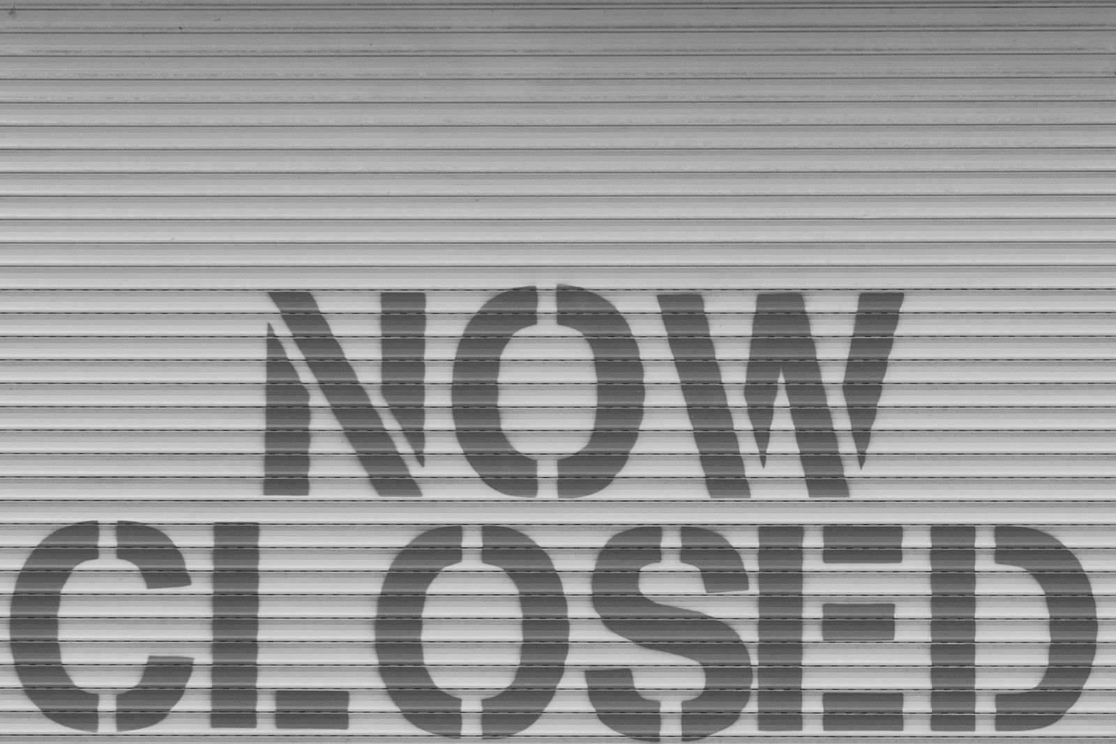 Tấm biển Now Closed gắn trên cửa cuốn kim loại, hình ảnh ẩn dụ cho việc BitMEX chính thức đóng cửa sàn giao dịch vào ngày 23/9/2026 sau hơn 11 năm hoạt động