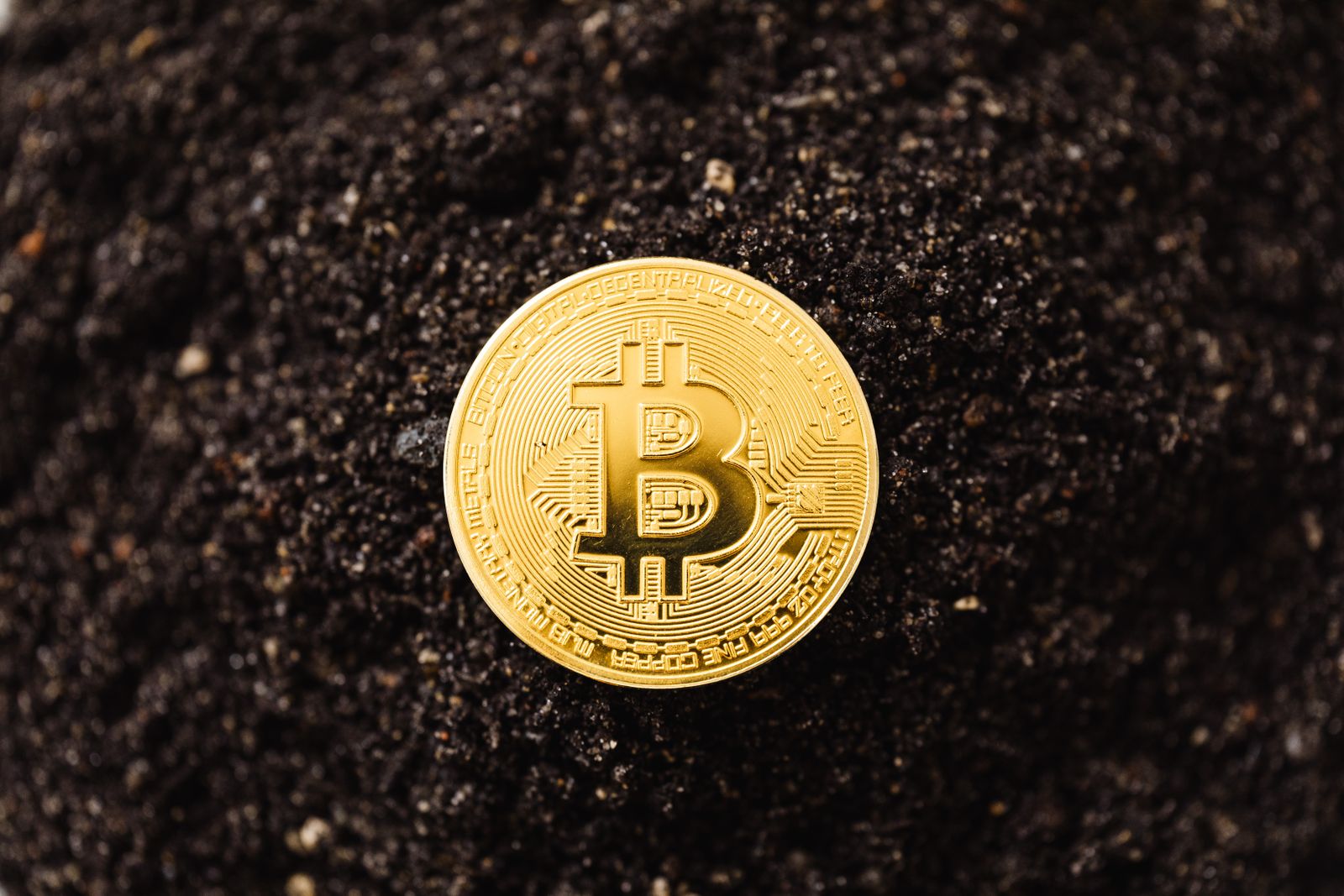 Đồng xu biểu tượng Bitcoin màu vàng đặt trên nền đất tối